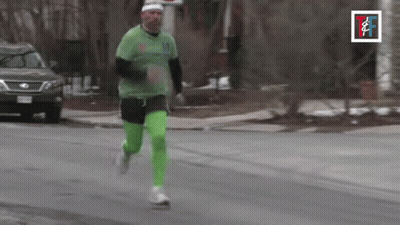 A Man In A Green Shirt And Green Pants Is Running Down A Street GIF