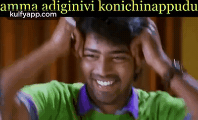 A Man In A Green Shirt And Purple Shirt Is Smiling And Holding His Head . GIF