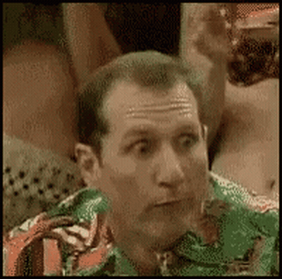 A Man In A Green Shirt And Tie Is Making A Funny Face . GIF