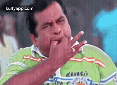 A Man In A Green Shirt Is Biting His Nails . GIF