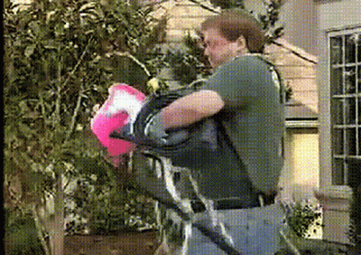 A Man In A Green Shirt Is Carrying A Pink Bag GIF