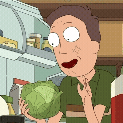 A Man In A Green Shirt Is Holding A Cabbage In Front Of A Refrigerator GIF