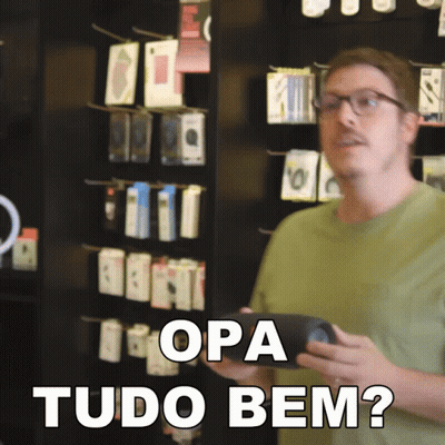 A Man In A Green Shirt Is Holding A Cell Phone And Says " Opa Tudo Bem " In White Letters GIF