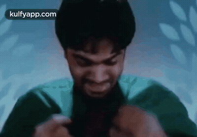 A Man In A Green Shirt Is Holding A Knife In His Hand And Smiling . GIF