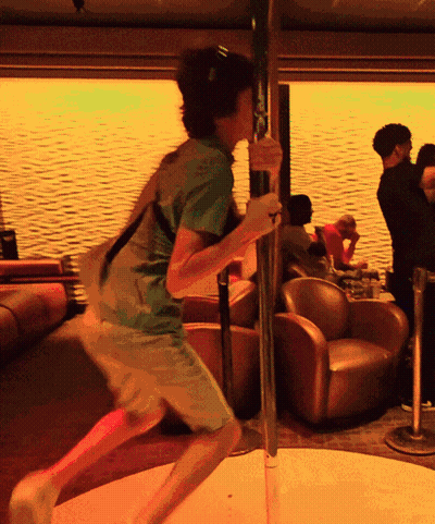 A Man In A Green Shirt Is Holding A Pole In A Room GIF