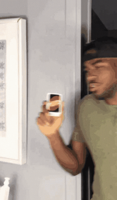 A Man In A Green Shirt Is Holding A Small White Object GIF