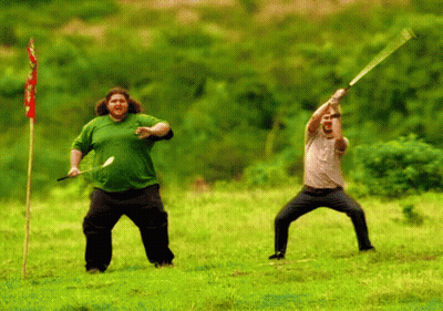 A Man In A Green Shirt Is Holding A Sword In A Field GIF