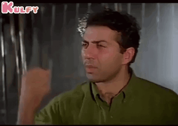 A Man In A Green Shirt Is Making A Funny Face While Holding His Fist Up . GIF