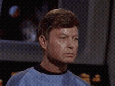 A Man In A Green Shirt Is Making A Funny Face While Sitting Down . GIF