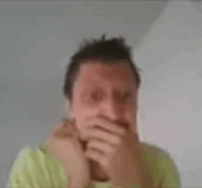 A Man In A Green Shirt Is Making A Funny Face With His Hands . GIF