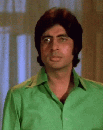 A Man In A Green Shirt Is Making A Funny Face . GIF