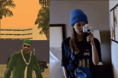 A Man In A Green Shirt Is Next To A Woman Holding A Camera GIF