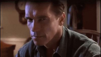 A Man In A Green Shirt Is Sitting In A Chair And Making A Funny Face . GIF