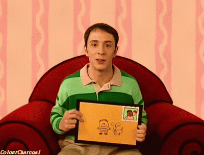 A Man In A Green Shirt Is Sitting In A Red Chair Holding A Drawing GIF