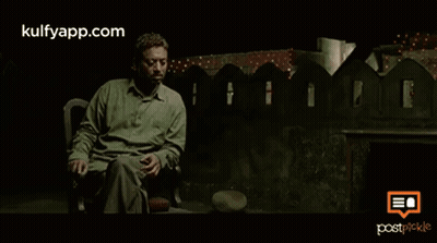 A Man In A Green Shirt Is Sitting In Front Of A Fence With The Website Kulfyapp.com On The Bottom Right GIF