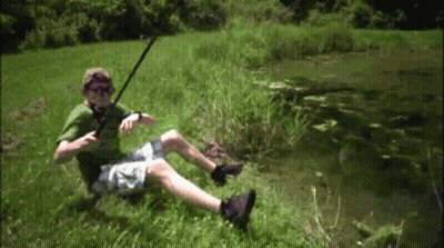 A Man In A Green Shirt Is Sitting In The Grass Holding A Fishing Rod GIF