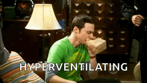 A Man In A Green Shirt Is Sitting On A Couch Eating A Paper Bag . GIF