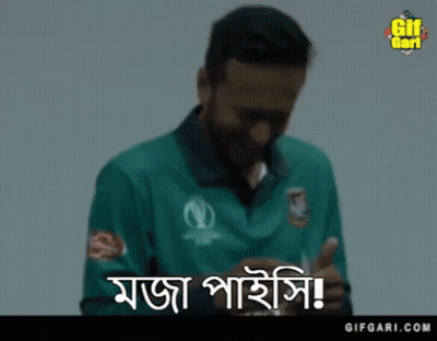 A Man In A Green Shirt Is Smiling While Holding A Card In His Hand . GIF