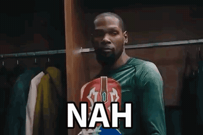 A Man In A Green Shirt Is Standing In A Locker Room With Clothes Hanging On The Racks And Says Nah . GIF