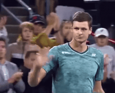 A Man In A Green Shirt Is Standing In Front Of A Crowd . GIF