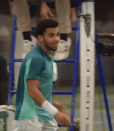 A Man In A Green Shirt Is Standing In Front Of A Ladder GIF