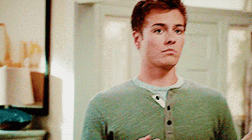 A Man In A Green Shirt Is Standing In Front Of A Mirror And Looking At The Camera . GIF