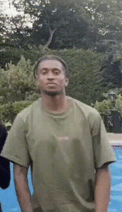 A Man In A Green Shirt Is Standing In Front Of A Swimming Pool GIF