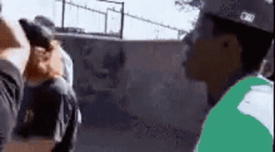 A Man In A Green Shirt Is Standing Next To A Man In A Black Shirt . GIF