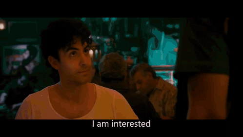 Man In Green Shirt Talking To Man In Dark Room GIF