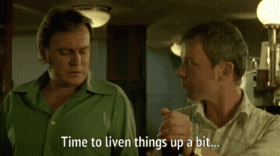 A Man In A Green Shirt Says " Time To Liven Things Up A Bit " To Another Man GIF