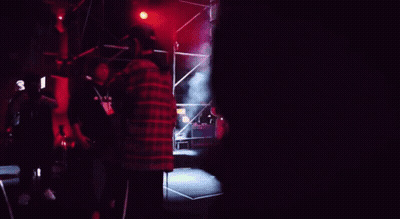 A Man In A Green Shirt Stands In Front Of A Crowd Of People GIF