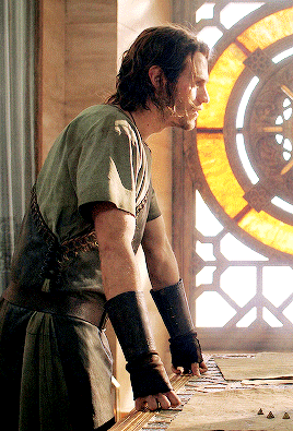 A Man In A Green Shirt Stands In Front Of A Window GIF