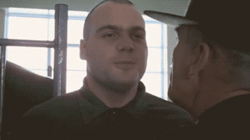 A Man In A Green Shirt Talks To Another Man In A Black Hat GIF