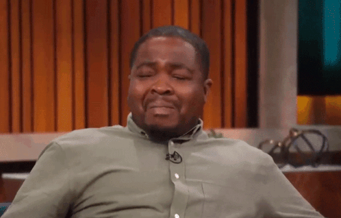 A Man In A Green Shirt With A Microphone On His Neck Is Making A Funny Face . GIF