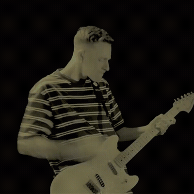 A Man In A Green Striped Shirt Is Playing A Guitar GIF