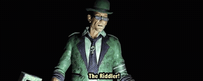 A Man In A Green Suit And Hat Is Holding A Cane With The Words The Riddler Written On It . GIF