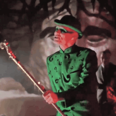 A Man In A Green Suit And Hat Is Holding A Gold Cane GIF