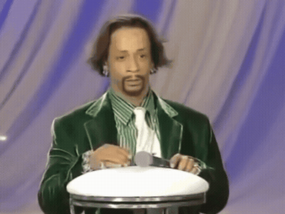 A Man In A Green Suit And Tie Holds A Microphone GIF