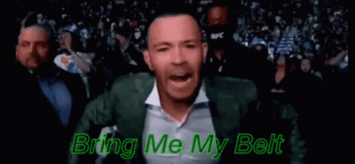 A Man In A Green Suit And White Shirt Is Standing In Front Of A Crowd And Singing . GIF