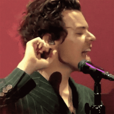 A Man In A Green Suit Is Singing Into A Microphone While Holding His Ear . GIF