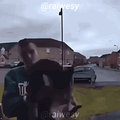 A Man In A Green Sweatshirt Is Standing In Front Of A Street With The Name @Raiwesy On The Bottom GIF