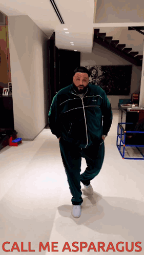 A Man In A Green Tracksuit Is Standing In A Hallway With The Words Call Me Asparagus Above Him GIF