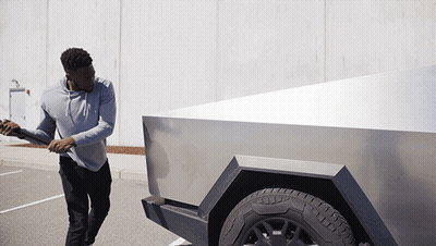 A Man In A Grey Hoodie Is Pushing A Silver Truck GIF