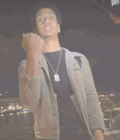 A Man In A Grey Jacket Is Holding A Stack Of Money In His Hand GIF