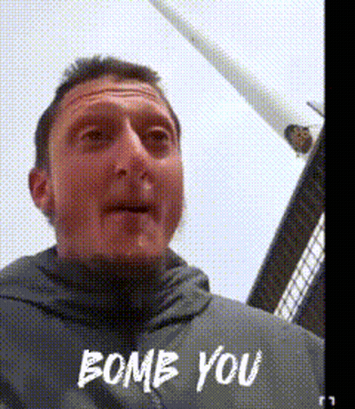 A Man In A Grey Jacket Says " Bomb You " In White Letters GIF