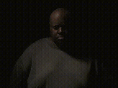 A Man In A Grey Reebok Shirt Looks At The Camera GIF