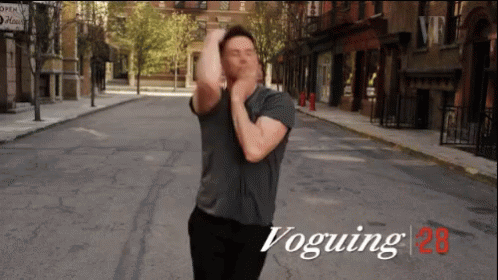 A Man In A Grey Shirt Is Dancing On A Street With The Words Voguing 28 On The Bottom GIF