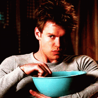 A Man In A Grey Shirt Is Holding A Blue Bowl Of Food GIF