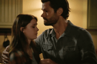 A Man In A Grey Shirt Is Hugging A Woman GIF