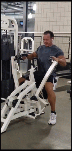 A Man In A Grey Shirt Is Using A Machine In A Gym That Has The Word Cybex On It GIF